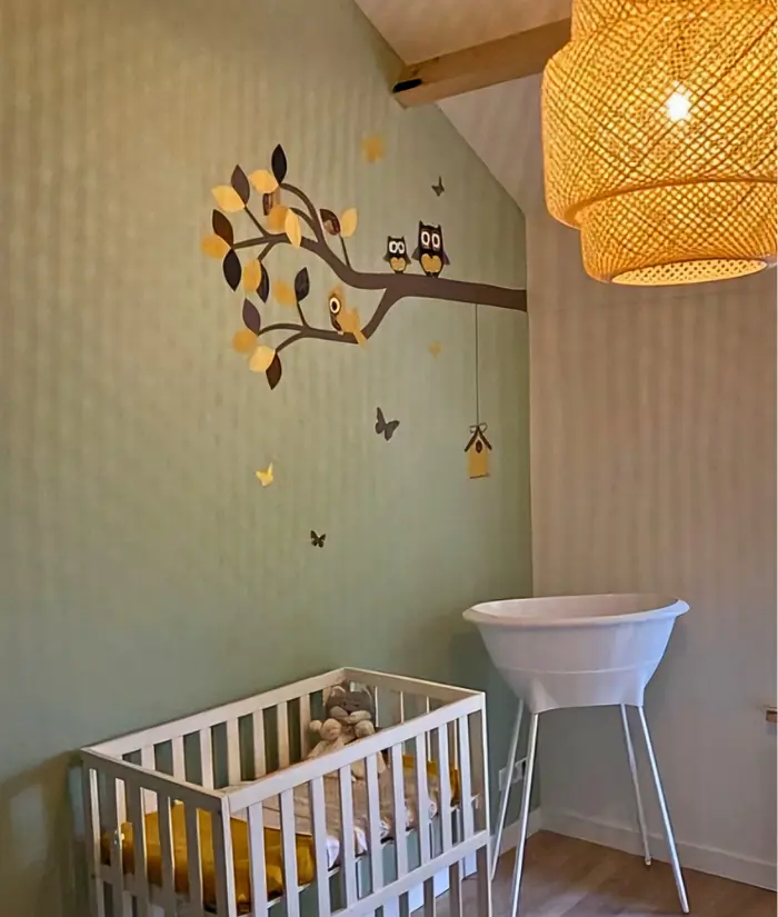 Okergele babykamer met een sierlijke uilentak muurdecoratie